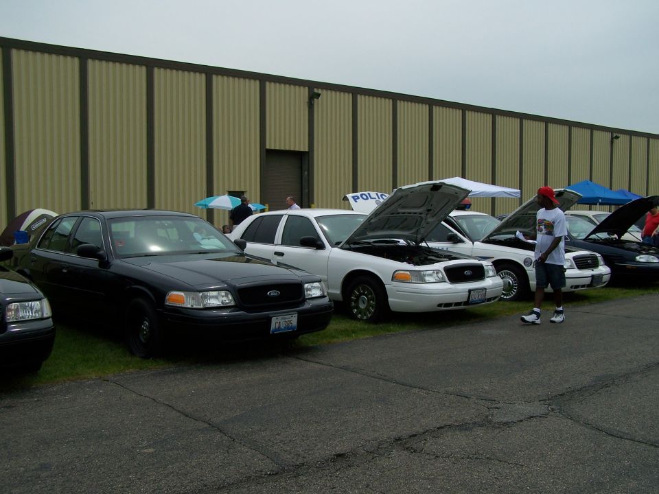 Several Ford Crown Victoria police cars lined up, one with hood open