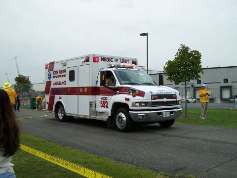 2003 Ford Crown Victoria - Ambulance with "Medic Unit" and "North Aurora Fire Protection District" markings is parked on a road.
