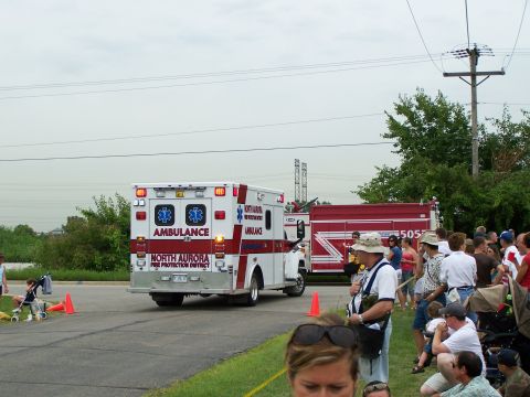 2003 Ford Crown Victoria - An ambulance and a fire truck are parked on a street, with a crowd of people observing.