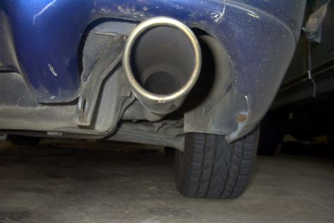 1994 Dodge Stealth - Close-up view of a car's exhaust pipe and the lower rear bumper, showing some damage.