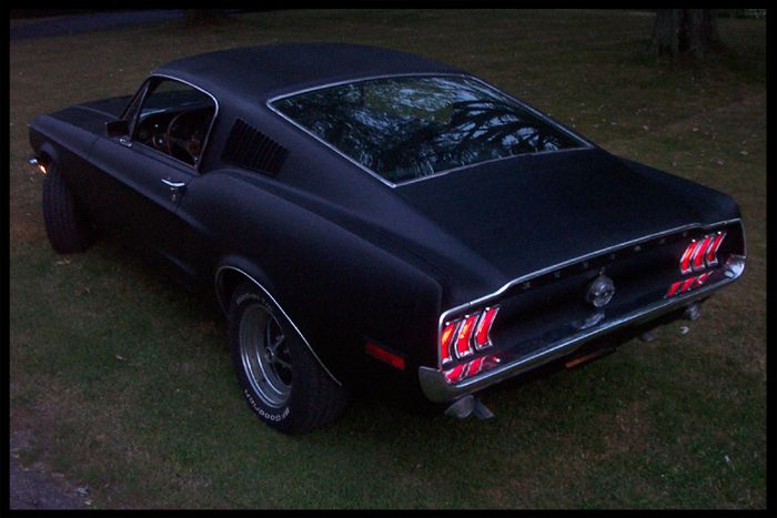Black 1967 Ford Mustang Fastback parked on grass, rear view
