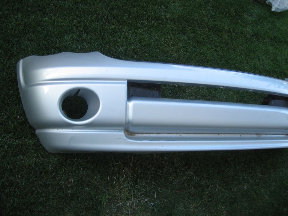 Silver front bumper with a circular cutout on the left side, resting on grass