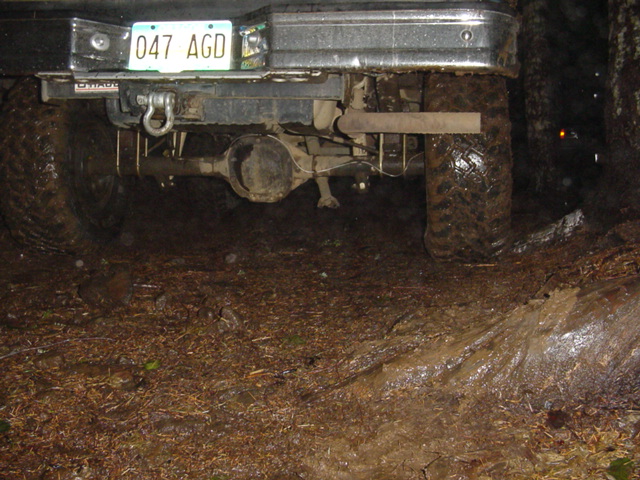 Rear underside of a lifted 4x4 truck at night showing axle and license plate