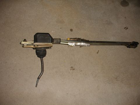 1993 Ford Taurus - A car's shift linkage assembly is shown lying on a concrete surface.