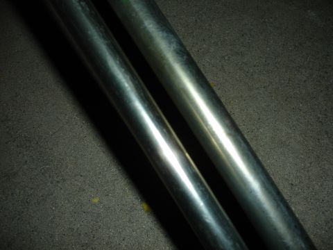 1993 Ford Taurus - Close-up view of two metallic pipes, possibly exhaust components, against a dark, textured background.
