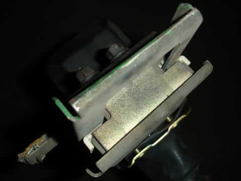 1993 Ford Taurus - A detailed view of a metal bracket assembly, bolts and a black rubber element, against a dark background.