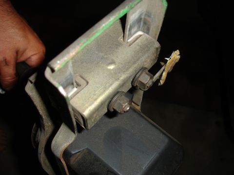 1993 Ford Taurus - A metal bracket assembly with visible bolts and a green painted edge is held by a hand.
