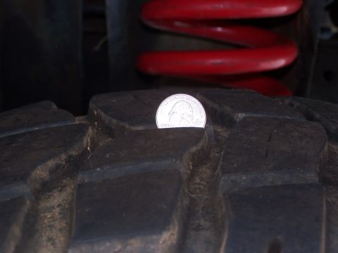 2007 Ford Bronco - A quarter is placed in the tire tread to show depth, with a red coil spring visible above.