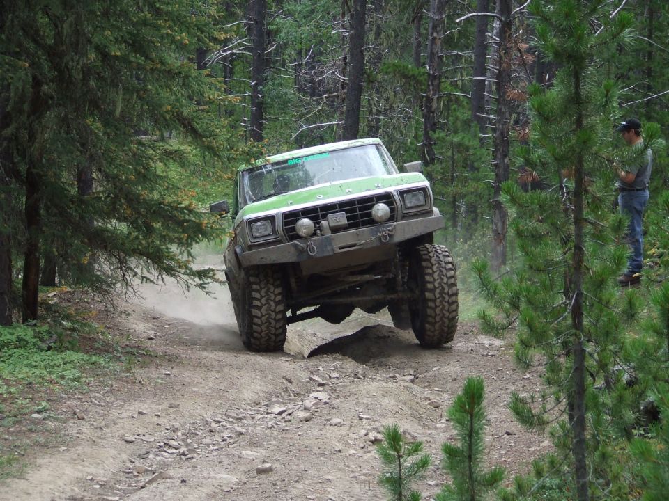 Green off-road truck on a dirt path, 1980s body style
