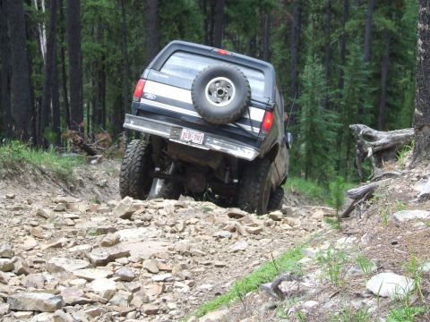 1990 Ford Bronco - This 1990 Ford Bronco navigates a challenging, rocky path through a dense forest.