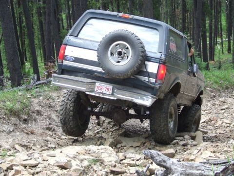 1990 Ford Bronco - This Ford Bronco navigates a rocky path through a dense forest.