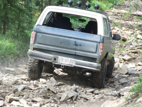1990 Ford Bronco - This SUV navigates a challenging rocky path, its rear license plate EYA-853 visible.