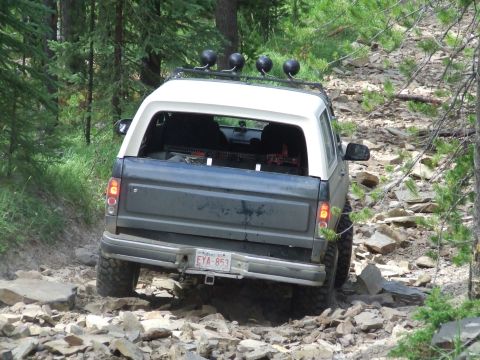 1990 Ford Bronco - Ford Bronco navigates a challenging rocky path through a forest.
