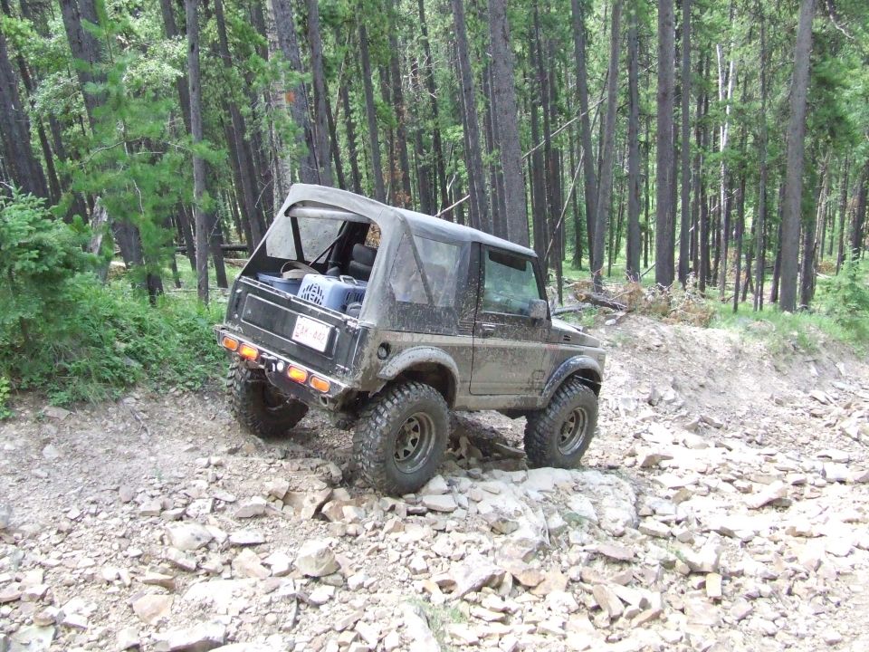 Suzuki Samurai with soft top on a rocky mountain trail, tires are muddy