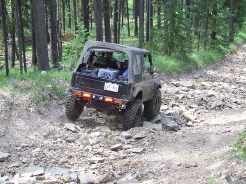 1990 Ford Bronco - This off-road vehicle tackles a challenging, rocky path through a wooded area.