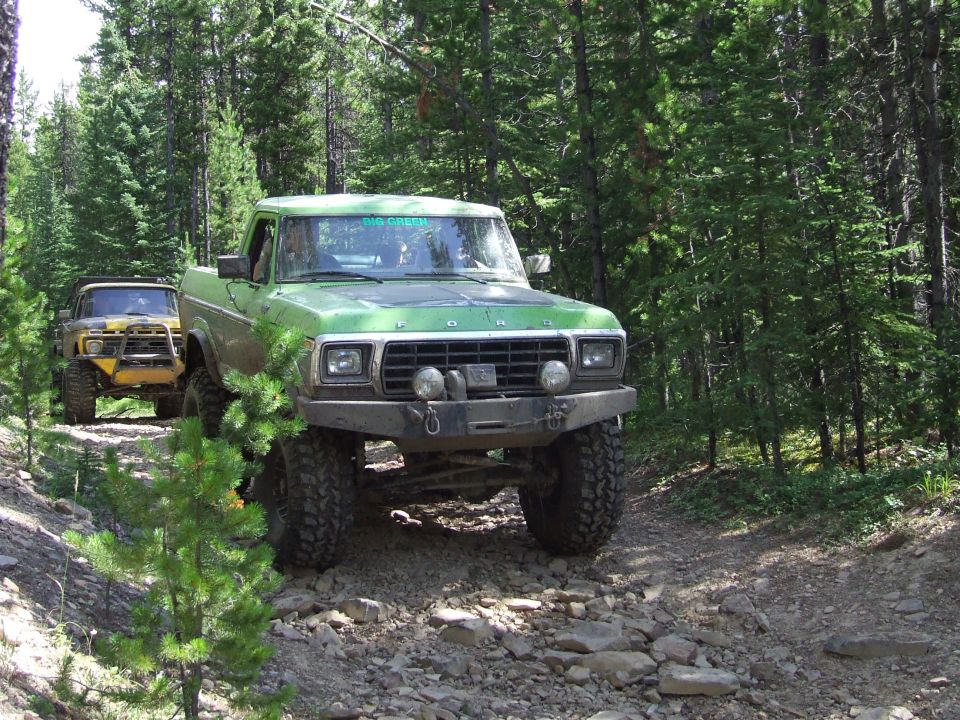 Green Ford F-Series truck with custom bumper and winch on a rocky trail