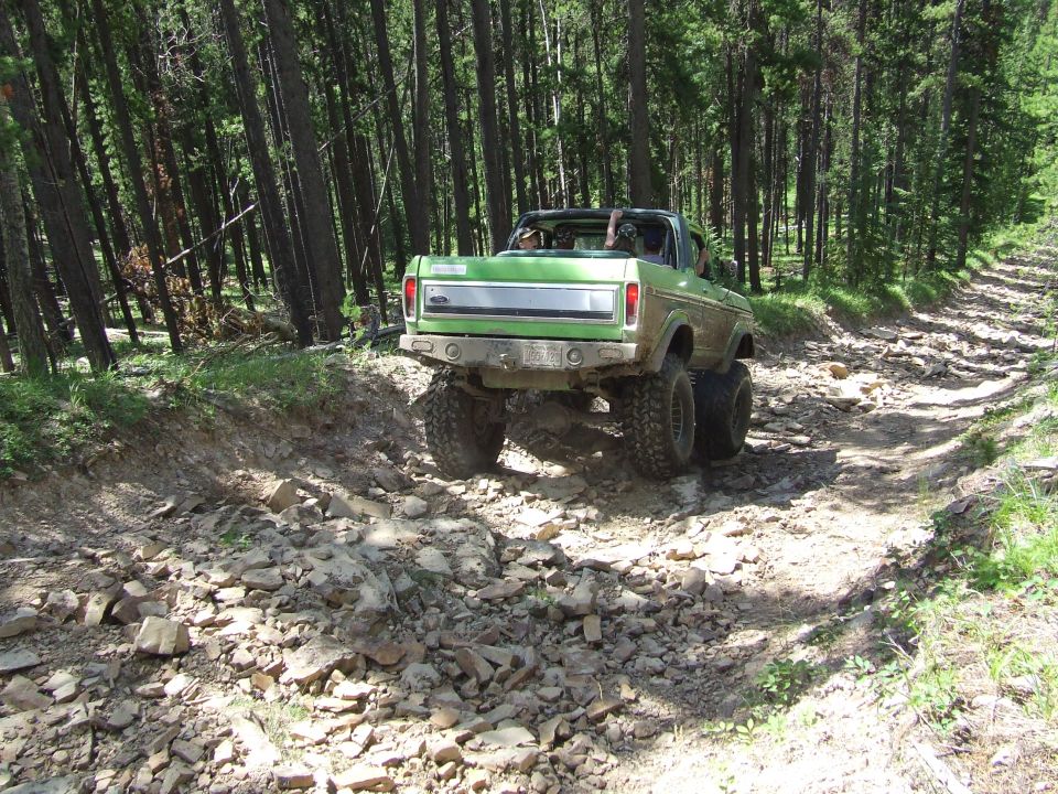 Green off-road truck with large tires on a rocky trail