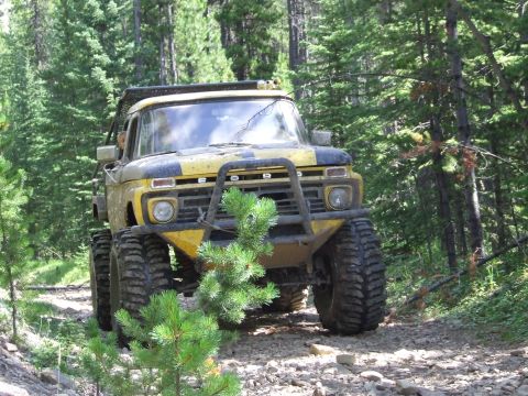 1990 Ford Bronco - Modified Ford F-Series truck navigates a rocky forest trail with large off-road tires.