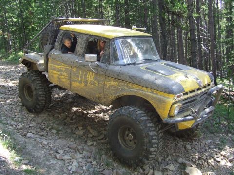 1990 Ford Bronco - This heavily modified pickup truck, likely from the mid-1960s, navigates a challenging off-road path.