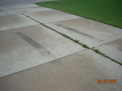 2000 Chevrolet Tahoe - Tire tracks are visible on a concrete driveway next to a lawn.lawn. grass lawn.lawn.