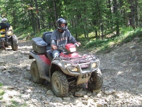 1990 Ford Bronco - Riding ATVs through a wooded area on a rough, rocky trail.