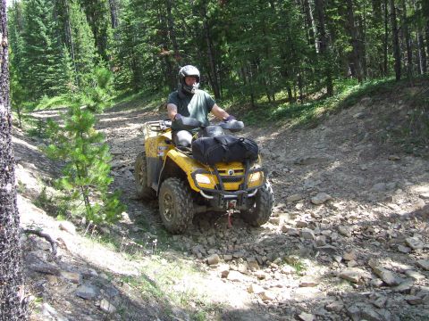 1990 Ford Bronco - A rider navigates a yellow ATV through a rocky, wooded trail during the Rocky Mountain Bronco Rally 2007.