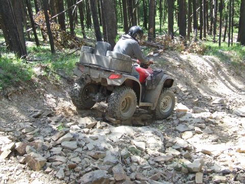 1990 Ford Bronco - An ATV rider navigates a challenging rocky path through a wooded area.