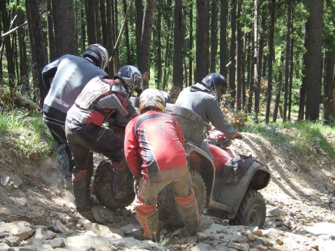 1990 Ford Bronco - ATV riders tackle a challenging, rocky path through a dense forest during an off-road event.