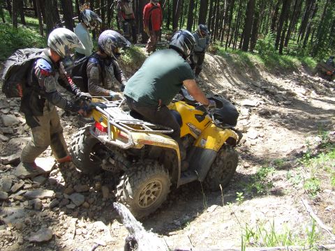 1990 Ford Bronco - Riders on a yellow Can-Am ATV navigate a challenging rocky trail through a forest.