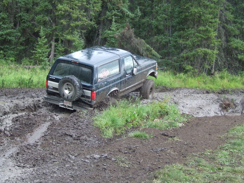 1990 Ford Bronco stuck in mud on a wooded trail
