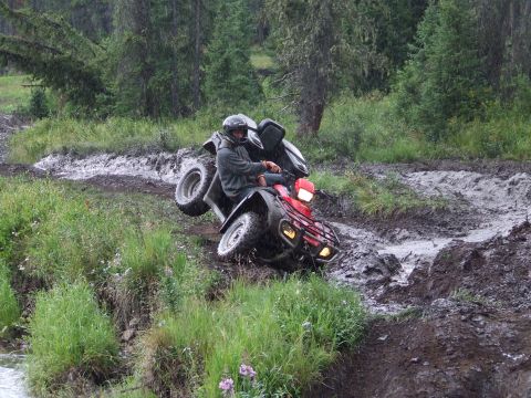 1990 Ford Bronco - An ATV rider struggles on a treacherous, muddy path during an off-road excursion.