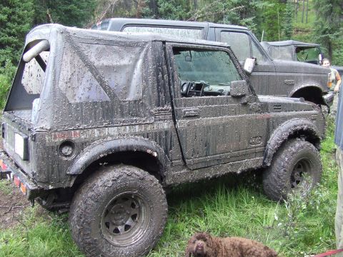 1990 Ford Bronco - A muddy Suzuki Samurai and a Ford Bronco are parked off-road.