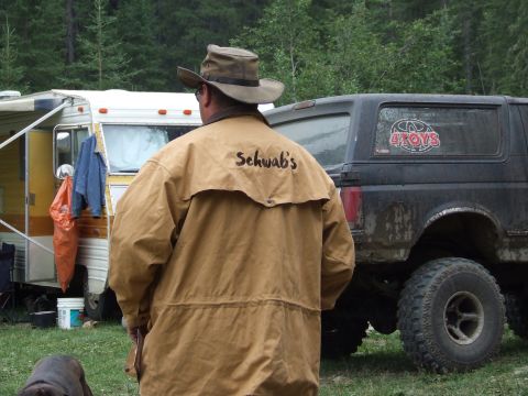1990 Ford Bronco - Man in jacket stands by RV and a lifted 1990 Ford Bronco at an outdoor event.