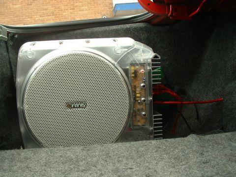 1989 BMW 3 Series - An Infinity subwoofer is visible in the trunk of a car, with its internal components and wiring exposed.