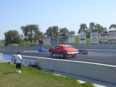 1997 Ford Crown Victoria - Drag racing action with a red muscle car at the starting line.