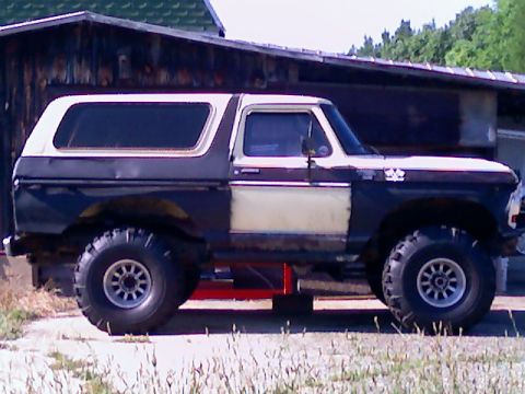 Side view of a dark blue and white Ford Bronco with aftermarket wheels and tires