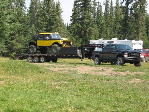 1995 Ford Bronco - A custom yellow pickup truck is loaded onto a trailer, with a black Ford pickup truck parked nearby.