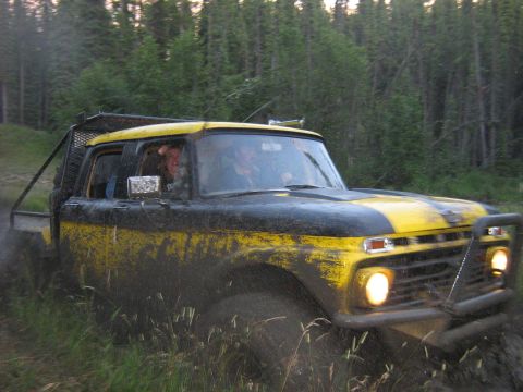 1995 Ford Bronco - This pickup truck is covered in mud while driving through a wooded off-road trail.