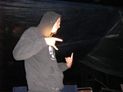1995 Ford Bronco - A person in a dark hoodie gestures with their hands in front of a black tarp.
