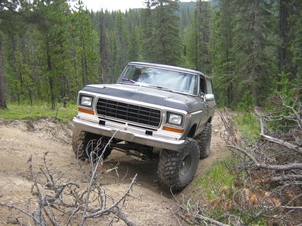 Ford Bronco on a dirt trail in a forest. Lifted suspension and large tires