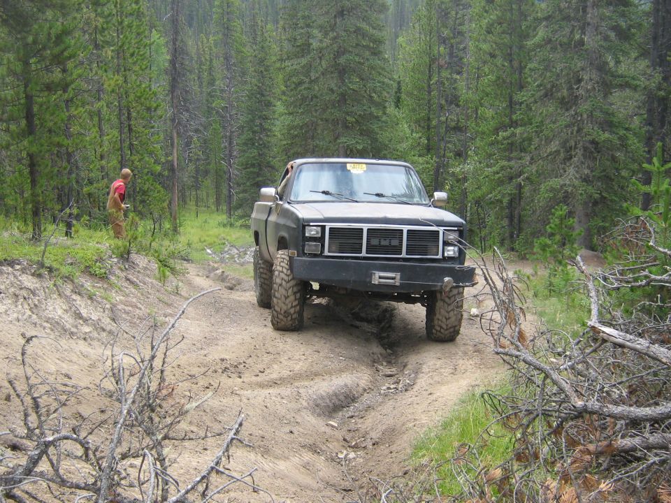 Black pickup truck with large tires on a dirt trail in a forest