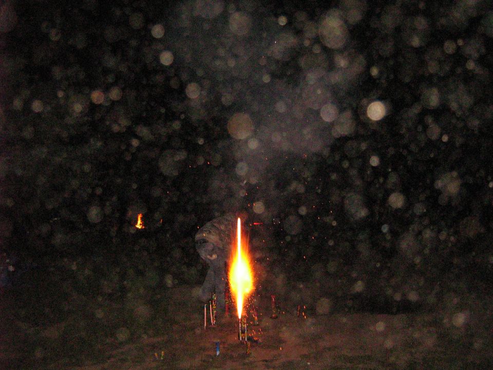 Person lighting fireworks at night with sparks and bokeh