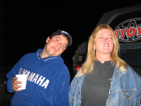 1995 Ford Bronco - Two people pose in front of a dark SUV at night.