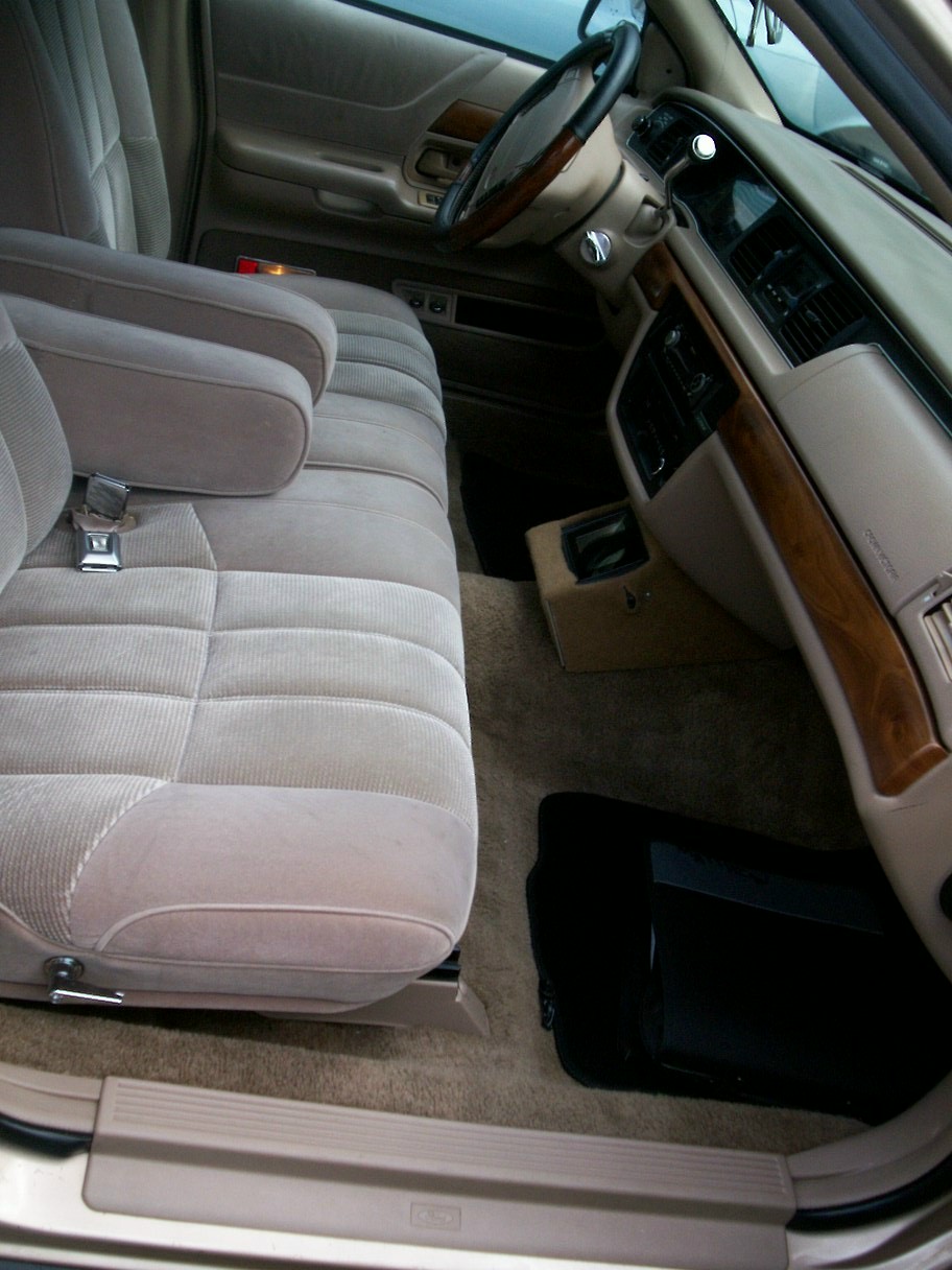 Tan fabric interior of a 1992 Ford Crown Victoria, showing front seats, dashboard, and steering wheel