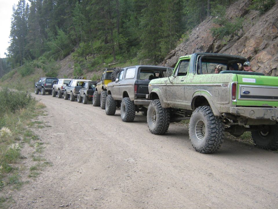 Green Ford Bronco with lifted suspension and large tires on a dirt road
