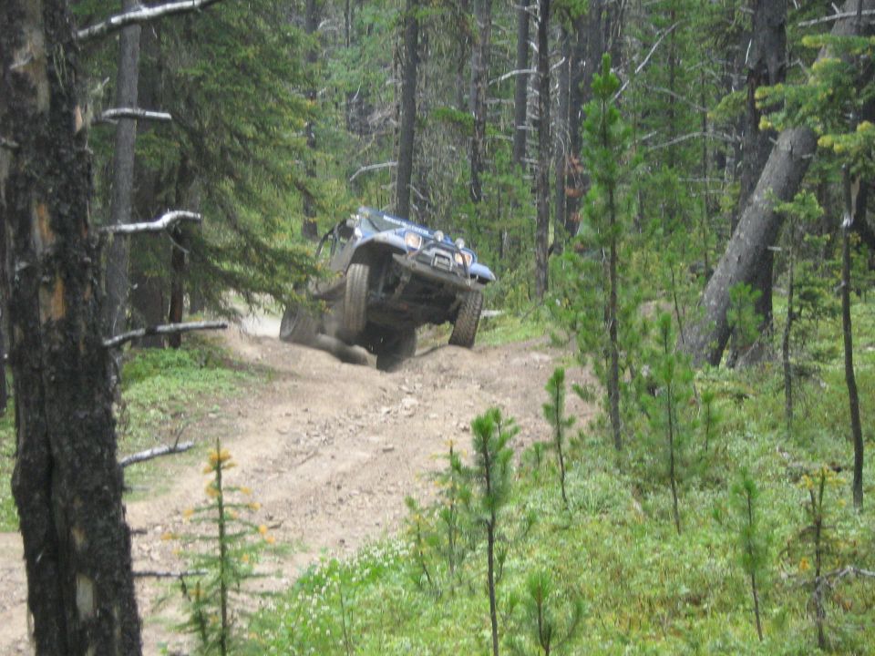 Off-road vehicle climbing a steep dirt hill in a forest