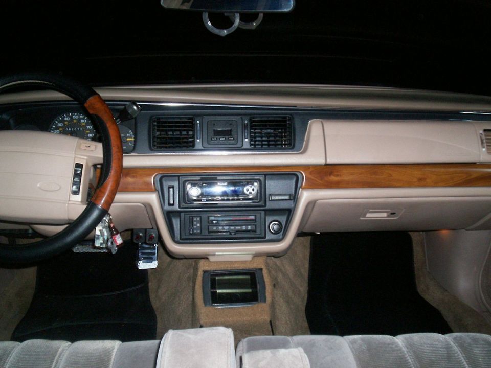 1992 Ford Crown Victoria interior dashboard with wood trim, aftermarket stereo, and tan upholstery