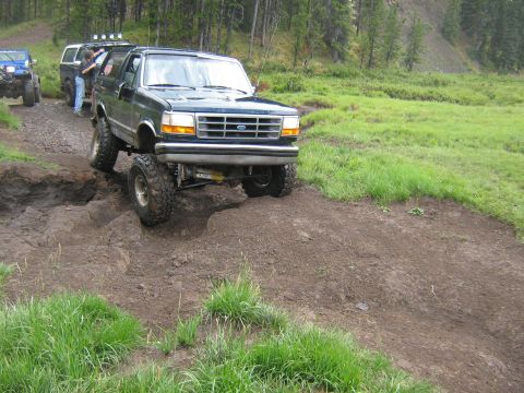 1995 Ford Bronco - A Ford Bronco tackles a challenging muddy obstacle on an off-road trail.