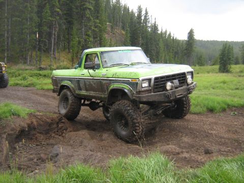 1995 Ford Bronco - This lifted pickup truck navigates a challenging muddy terrain during an off-road excursion.