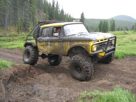 1995 Ford Bronco - This heavily modified Ford truck navigates a challenging muddy terrain with its large off-road tires.
